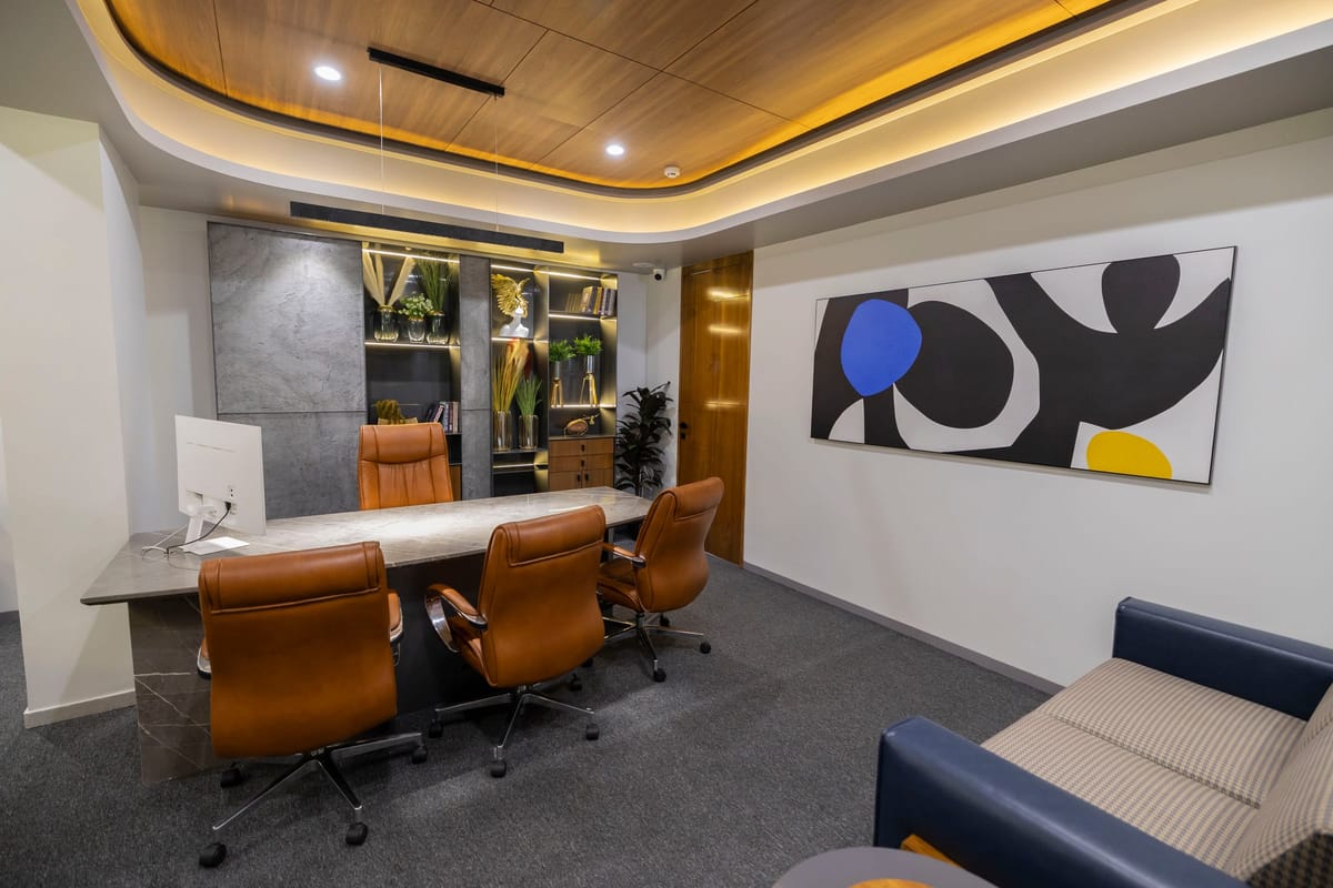 A boardroom with a long marble table, tan leather chairs and an abstract painting on the wall