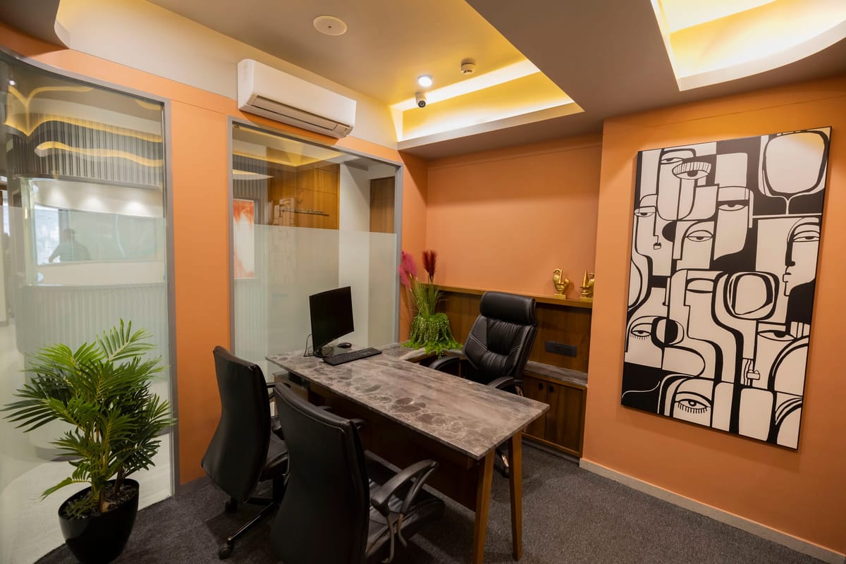 A consultation office in warm orange tones, with a wooden desk and a patterned painting